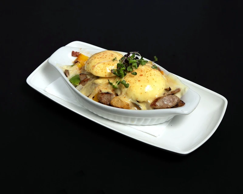 Eggs Benedict with hollandaise, potatoes and greens at Rise & Dine Restaurant